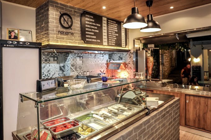 No Name interior with brick, wood, black menu boards and gyros grill