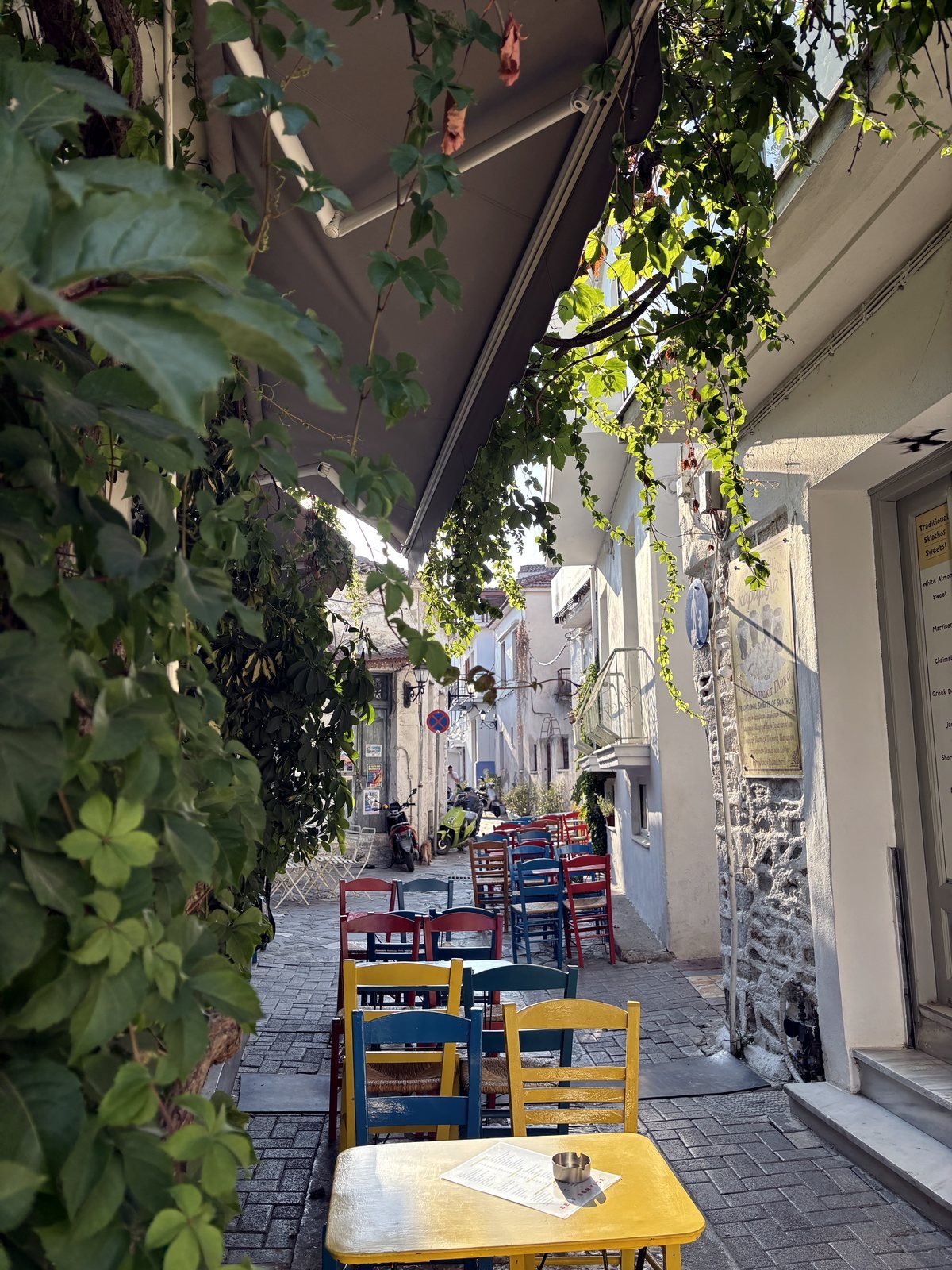Outdoor tables and colourful chairs near No Name in Skiathos Town